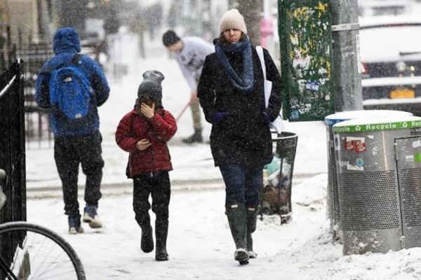 Một phụ nữ và một đứa trẻ đi bộ qua một cơn bão tuyết ở New York ngày 3/3 - Ảnh: Reuters