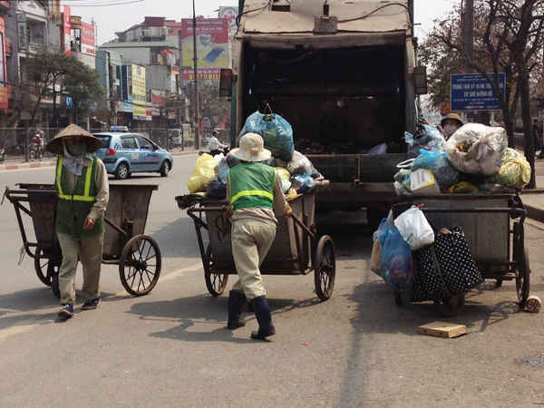 Những chị lao công thi nhau đẩy các xe thu gom rác cao ngất ngưởng vào xe tải để chở đi xử lý