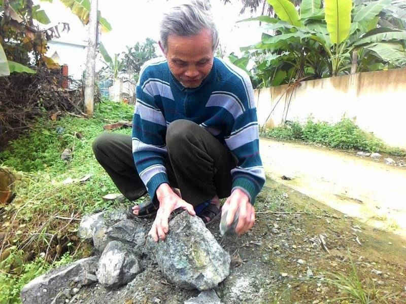Ông Vũ Văn Hán đang chỉ cho chúng tôi những viên đá có chứa chất amiăng độc hại mà bà con lấy về kè giếng, làm đường.