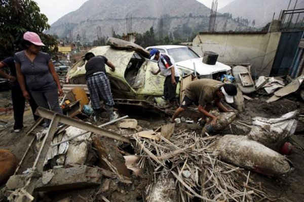 Nhiều người đang dọn dẹp mảnh vỡ của những chiếc xe ô tô và những ngôi nhà sau vụ lở đất ở Chosica, Pê-ru ngày 24/3 (Ảnh: Reuters)