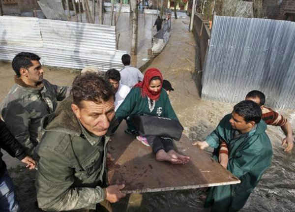 Một người phụ nữ ốm yếu ngồ trên một tấm ván gỗ, được mọi người di chuyển đến một nơi an toàn hơn vì nhà của cô bị ngập một phần sau khi ngớt mưa ở Srinagar ngày 30/3 - Ảnh: Reuters
