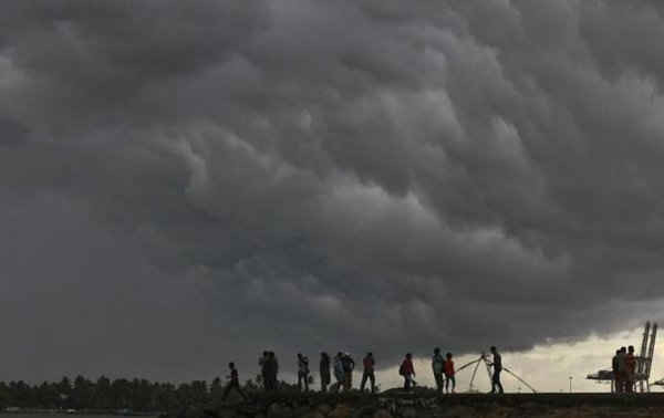 Nhiều người đứng trên bờ biển tìm cách chống lại hiện tượng những đám mây trước thời tiết gió mùa tụ lại trên Bờ biển Arabian ở Kochi, bang Kerala phía nam Ấn Độ ngày 4/6/2012 (Ảnh: Reuters)