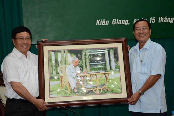 Phó Thủ tướng, Bộ trưởng Bộ Ngoại giao Phạm Bình Minh (bìa trái) trao tặng bức ảnh chân dung Bác Hồ cho ông Trần Minh Thống - Bí thư Tỉnh ủy Kiên Giang. 