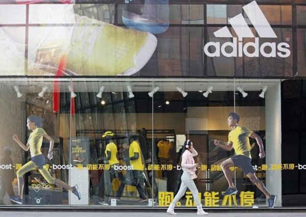 Một phụ nữ đi qua một cửa hàng Adidas tại khu mua sắm ở Bắc Kinh ngày 25/3/2013. Ảnh: Reuters/Kim Kyung-HOON