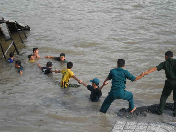 Lực lượng công an, quân sự hỗ trợ người dân trục vớt tài sản bị sụp xuống sông.