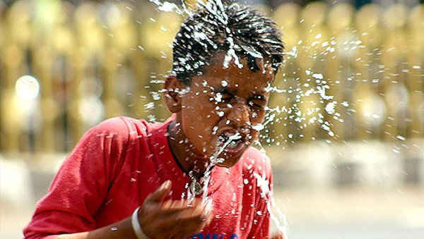 Một cậu bé rửa mặt bằng nước lạnh để hạ nhiệt bản thân khỏi đợt nắng nóng 