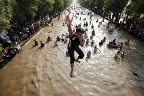 Một cậu bé và nhiều người khác nhảy vào một con kênh để làm mát vào một ngày nắng nóng ở phía đông thành phố Lahore, Pakistan ngày 9/6/2013. Ảnh: REUTERS / Mohsin RAZA