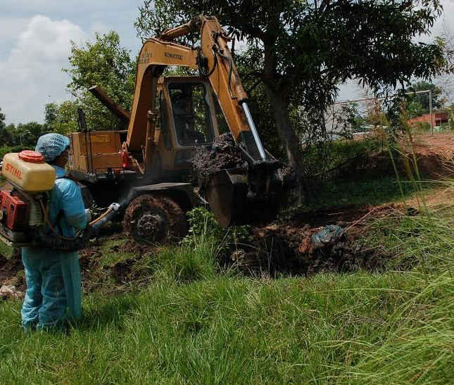 Nhân viên y tế phun thuốc khử trùng vào các hố chôn lấp rác thải y tế trái phép ở khu đất sân vận động P.II, TP.Tây Ninh.