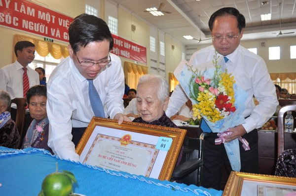 Phó Bí thư Thường trực Thành ủy TPHCM Võ Văn Thưởng (trái) trao tặng danh hiệu “Bà mẹ Việt Nam Anh hùng” cho một người  Mẹ. 