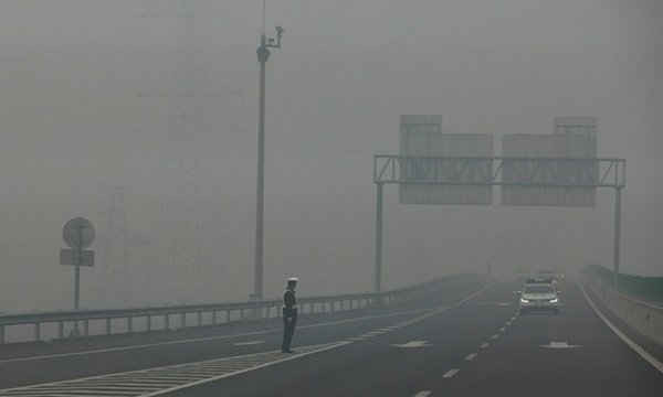 Việc quan sát một sĩ quan cảnh sát giao thông đứng trên đường cao tốc là hết sức khó khăn bởi mức độ ô nhiễm nghiêm trọng tại tỉnh Hà Bắc, Trung Quốc vào ngày 26/11/2014. Ảnh: Diego Azubel / EPA