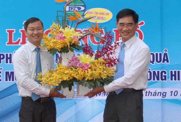 Phó Chủ tịch UBND tỉnh Đồng Nai Trần Văn Vĩnh (bên phải) trao tặng hoa chúc mừng cho ông Cao Tiến Sỹ - Trưởng Ban Quản lý các KCN Đồng Nai