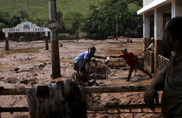 Ngày 7/11, những người đàn ông lấy một chiếc túi từ ngôi nhà bị ngập bùn sau sự cố vỡ đập tại Brazil. Ảnh: Reuters/Ricardo Moraes