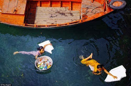 Hai cô bé bơi qua một con sông để nhặt những  chiếc chai nhựa - Tác giả: Thu Huỳnh