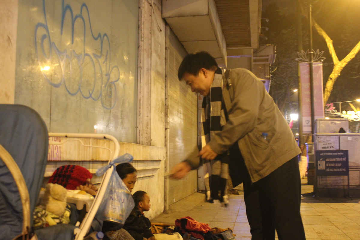 Một người đàn ông tặng tiền cho người vô gia cư trên đường Tràng Thi