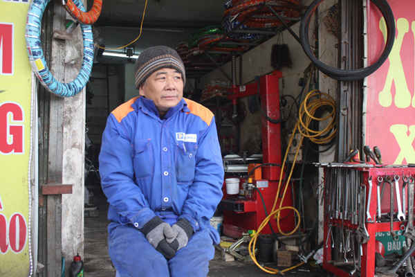 Bác Tuấn Phương (55 tuổi), thợ sửa xe máy thu mình lại trước cửa hàng của mình. Bác chia sẻ chưa năm nào thấy rét như năm nay.