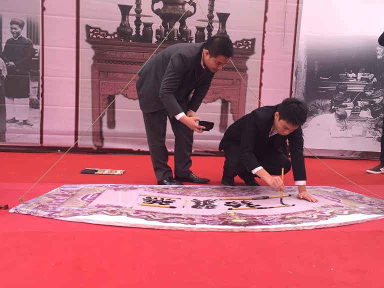 Thư pháp gia trẻ Nguyễn Tô Tâm An (sinh viên Học viện Ngoại giao) thể hiện khả năng viết chữ thư pháp trên bức hoành phi