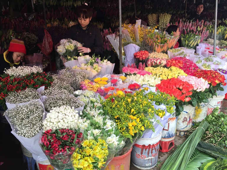 Chị Đỗ Thị Miền, kinh doanh sạp hoa ở chợ Quảng An được 10 năm thành thơi xếp hoa khi cửa hàng vẫn còn vắng khách