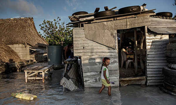 Một bé gái lội qua dòng nước biển tràn ngập ngôi nhà và ngôi làng của bé. Người dân Kiribati đang chịu áp lực phải chuyển đi nơi khác do mực nước biển dâng khoảng một phần hai inch mỗi năm. Ảnh: Jonas Gratzer / LightRocket qua Getty Images