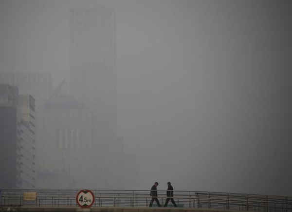 Người dân đi qua cây cầu dành cho người đi bộ vào một ngày ô nhiễm nặng ở Bắc Kinh, Trung Quốc, ngày 3/1/2016. Ảnh: REUTERS / Kim Kyung-HOON