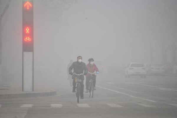 Nhiều người đeo khẩu trang đang đạp xe trên con phố đầy sương khói ở Liêu Thành, tỉnh Sơn Đông, Trung Quốc ngày 12/2/2016. Ảnh: REUTERS / STRINGER