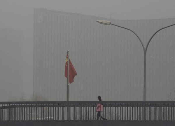 Một người phụ nữ đeo khẩu trang đang đi trên cầu vượt dành cho người đi bộ vào một ngày ô nhiễm nặng ở Bắc Kinh, ngày 25/12/2015. Ảnh: REUTERS/KIM KYUNG-HOON
