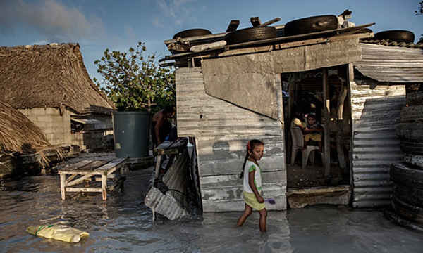 Một bé gái lội qua dòng nước biển làm ngập ngôi nhà và ngôi làng của bé ở Kiribati. Ảnh: Jonas Gratzer / LightRocket qua Getty Images