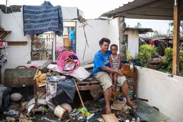Bà Kalisi, người Fiji đang ôm cậu con trai 3 tuổi, tên là Tuvosa trên một chiếc giường cùng những tàn tích của ngôi nhà bị hư hỏng do bão Winston xảy ra ở quận Rakiraki, tỉnh Ra Fiji ngày 24/2/2016. Ảnh: REUTERS / UNICEF-SOKHIN