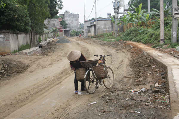 Bà Bùi Thị Định (thôn Cổ Rùa, xã Phú Mãn) dừng xe để chằng lại 1 rổ và 2 sọt rau cho chắc chắn vì lo ngã xe do đường xấu