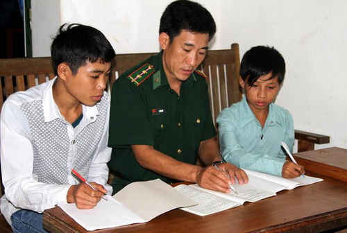 Chiến sỹ Đồn biên phòng Si Ma Cai (Lào Cai) giúp dân địa phương xóa mù chữ.