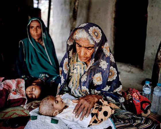 Một cụ già sống trong gia đình không có nhà vệ sinh và các cơ sở vật chất liên quan đến nước đang chăm sóc bé Shahbaz 4 tháng tuổi. Em bé này đang bị tiêu chảy và ói mửa. Tại Pakistan, hơn 40.000 trẻ em chết mỗi năm vì tiêu chảy do không có nước an toàn để sử dụng và thiếu nhà vệ sinh cơ bản. Trên thế giới, tiêu chảy là kẻ giết người lớn thứ hai đối với trẻ em dưới 5 tuổi. Ảnh: Mustafah Abdulaziz / WaterAid