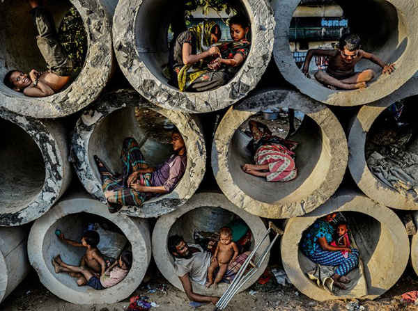 Theo một báo cáo của chính phủ, tổng số người ăn xin khắp Bangladesh hiện nay là hơn 900.000 người. Hoàn cảnh của những người ăn xin trong nước xuất hiện mâu thuẫn với quyền sống và quyền tự do di chuyển. Đây đều là những quyền cơ bản của hiến pháp Bangladesh. Có các cáo buộc tra tấn về thể chất, tinh thần và thậm chí tình dục đối với người dân ở các trung tâm trú ẩn. Điều này khiến nhiều người vô gia cư tìm kiếm bất cứ nơi nào ở các con đường làm nơi trú ẩn. Ảnh: Faisal Azim
