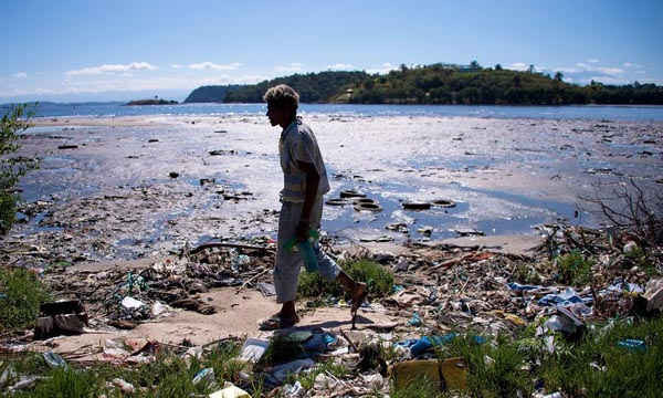 Một người đàn ông đi dọc bờ vịnh Guanabara bị ô nhiễm gần Rio de Janeiro. Ảnh: Buda Mendes / Getty Images