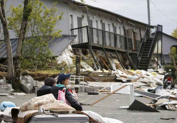 Một sinh viên đại học (bên phải) ngồi thất thần trước căn hộ bị sụp đổ của mình do động đất tấn công thị trấn Minamiaso, quận Kumamoto, miền nam Nhật Bảnvào ngày 16/4/2016. tín dụng bắt buộc. Ảnh: Reuters/Kyodo