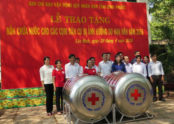 Đại diện Hội Chữ thập đỏ tỉnh Bình Phước trao tặng tượng trưng bồn chứa nước sạch cho đại diện các cụm dân cư ở huyện Lộc Ninh