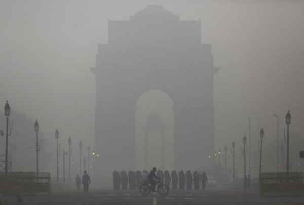 Một người đàn ông đạp xe bên cạnh đoàn lính Ấn Độ đang diễu hành trước India Gate trong một buổi sáng sương mù dày đặc ở New Delhi, Ấn Độ vào ngày 1/12/2015. Ảnh: REUTERS / ANINDITO MUKHERJEE