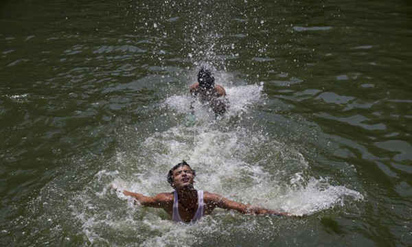 Những nam thanh niên bơi để làm mát cơ thể khi nhiệt độ kỷ lục chạm tới ngưỡng 51 độ C được ghi nhận tại TP Phalodi của Ấn Độ. Ảnh: Tsering Topgyal / AP