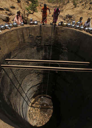 Những phụ nữ cố gắng lấy nước uống từ một vũng nước nhỏ - những giọt nước cuối cùng còn sót lại ở một cái giếng tại Bhakrecha Pada thuộc bang Maharashtra. Ảnh: Rajanish Kakade / AP