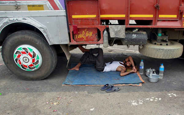 Một người đàn ông ngủ tạm trong bóng râm dưới gầm xe tải ở Agartala, bang Tripura, đông bắc Ấn Độ. Ảnh: Jayanta Dey / Reuters
