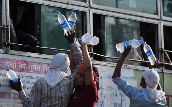Những người bán hàng rong đưa các chai nước cho hành khách trên xe buýt ở Allahabad. Ảnh: Sanjay Kanojia / AFP / Getty Images