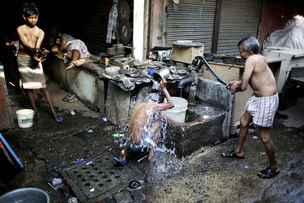 Công nhân tắm tại một giếng khoan công cộng vào một buổi sáng nóng bức ở Delhi. Ảnh: Altaf Qadri / AP