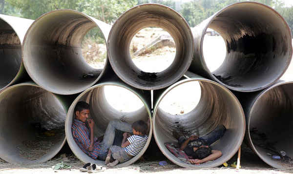 Người dân tránh nhiệt độ nóng nực bằng cách trú mình trong đường ống nước không dùng đến ở Delhi. Ảnh: Harish Tyagi / EPA