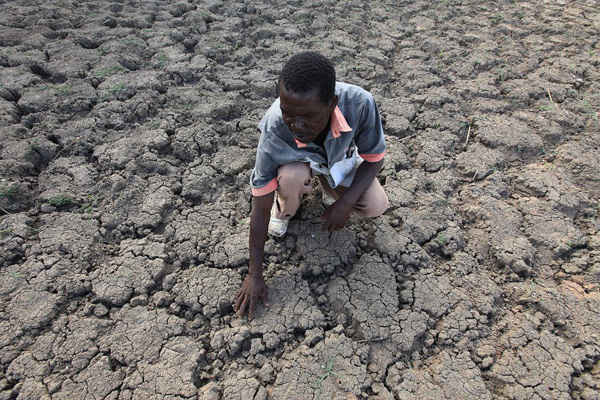Tại huyện Chivi của đất nước Zimbabwe, Last Zimaniwa chạm tay vào mặt đất khô cằn tại nơi từng là nguồn nước đáng tin cậy, nhưng đã trở nên cạn kiệt kể từ khi thiếu mưa. Ảnh: Tsvangirayi Mukwazhi / AP