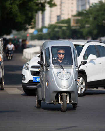 Một người đàn ông lái chiếc xe điện ba bánh ở thủ đô Bắc Kinh. Xe điện được sản xuất với hình dáng và kích thước đa dạng bởi vì các nhà sản xuất cố gắng đáp ứng nhu cầu của người dân thành phố. Những người lái xe 3 bánh chủ yếu là những người có tuổi. Ảnh: Sean Gallagher