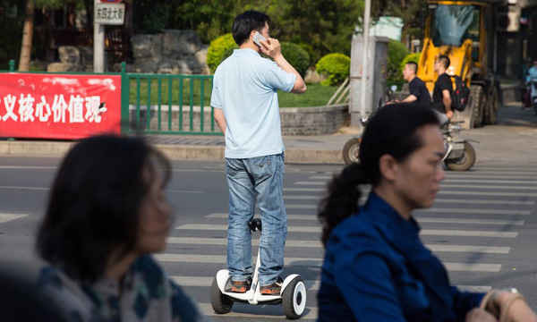 Người đàn ông vừa nói chuyện qua điện thoại vừa lái xe xcutơ điện hai bánh thông minh ở thủ đô Bắc Kinh. Ảnh: Sean Gallagher