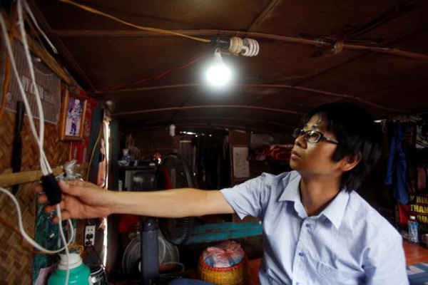 Ông Lê Vũ Cường bật một bóng đèn của hệ thống năng lượng gió được làm từ xô nhựa trên một chiếc thuyền tại 