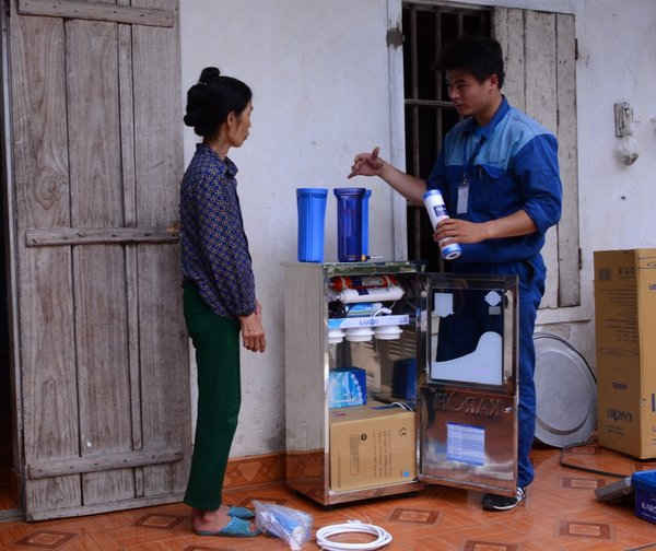 Hình ảnh Bà Quế gầy gò vì bệnh tật đang được kỹ thuật viên hướng dẫn sử dụng máy lọc nước