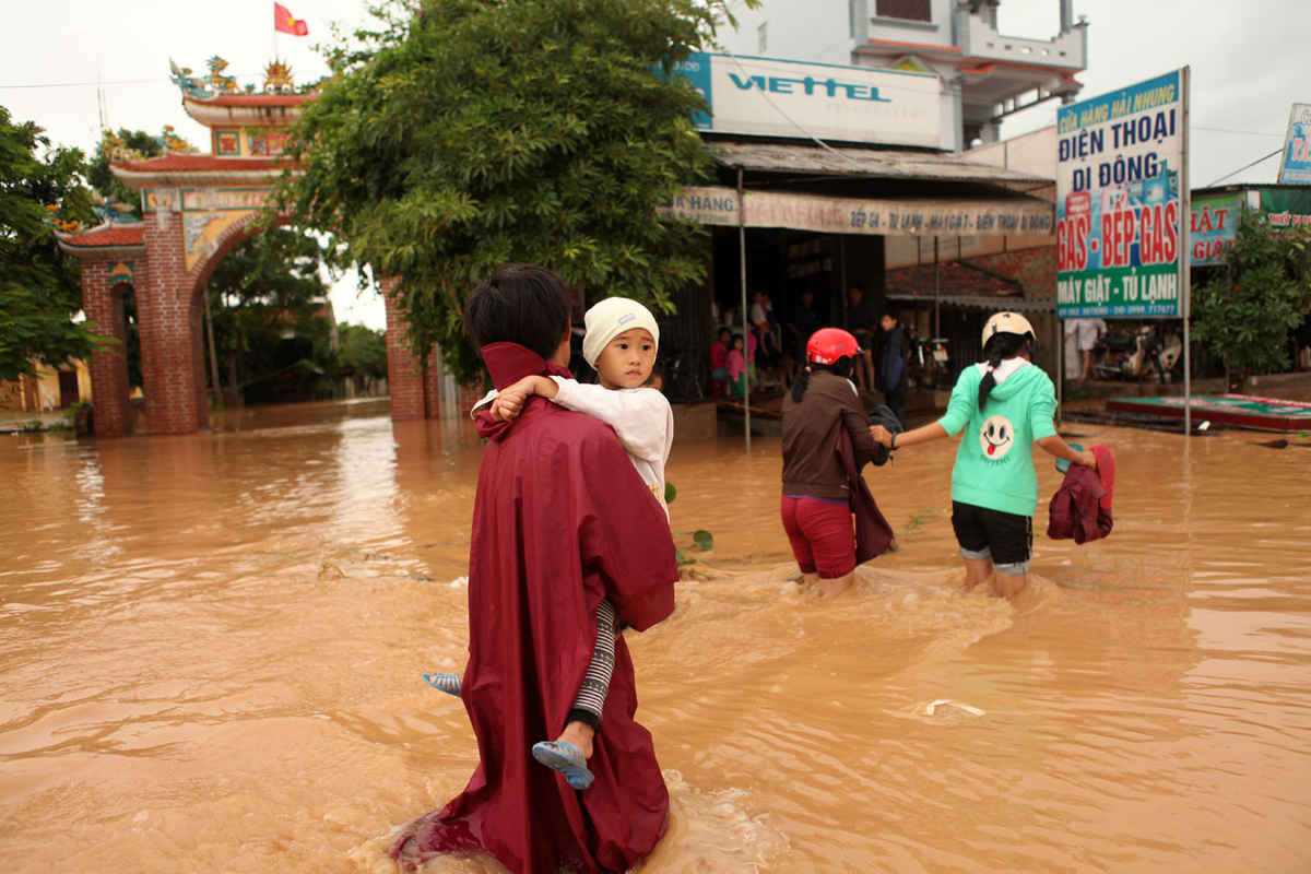 Người dân di chuyển qua vùng ngập lụt tại Quảng Bình. Ảnh: MH