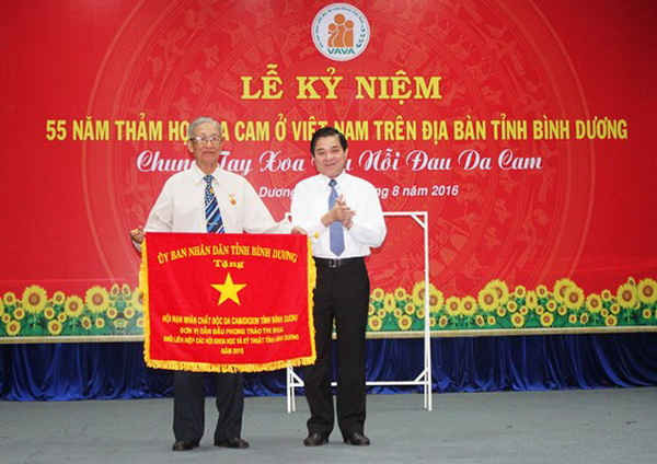 Ông Trần Thanh Liêm - Phó Chủ tịch UBND tỉnh Bình Dương (bên phải) trao tặng Cờ thi đua của UBND tỉnh cho Hội nạn nhân chất độc da cam/Dioxin tỉnh