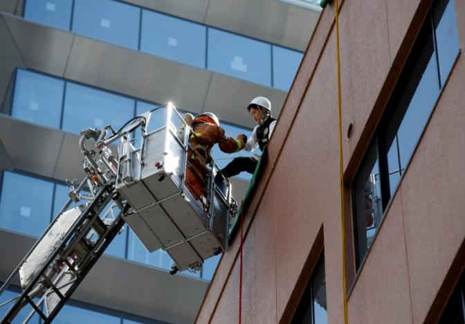 Một nhân viên cứu hỏa cùng chiếc cần cẩu giải cứu một người đàn ông nhập vai là một người đang bị cô lập trên đỉnh của một tòa nhà trong cuộc tập trận