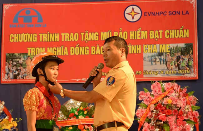 Đại diện Ban ATGT tỉnh Sơn La hướng dẫn các em học sinh cách đội mũ bảo hiểm đúng cách